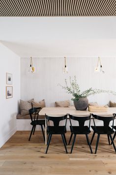 a dining room table with black chairs and a potted plant