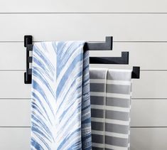 three towels are hanging on a towel rack in front of a white and gray wall