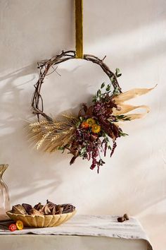 a wreath hanging on the wall next to a bowl with dried flowers and other decorations