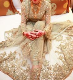 a woman sitting on top of a bed in a wedding dress with gold sequins