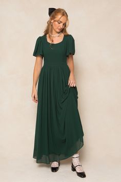 Twirl in style with the Abbie Dress in Emerald Chiffon. The flowy chiffon fabric and subtle sweetheart neckline provide a romantic touch, while the short bell sleeves and maxi-length skirt with functional pockets add a playful twist. This dress is not only the ultimate fall bridesmaids silhouette, but perfect for date night, special events, church and more. With a hidden back zipper, princess seams on the bodice and full lining, you simply can't go wrong. This women's dress is available in up to Moss Colored Dress, Dark Green Modest Dress, Formal Winter Wedding Guest Dress Classy, Lotr Bridesmaid Dresses, Green Winter Bridesmaid Dresses, Modest Christmas Dresses, Green Dresses For Wedding, Formal Dresses Long Modest, Eucalyptus Dress