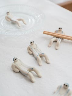 three small plastic animals sitting on top of a white table cloth next to chopsticks