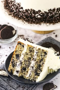 a slice of cake sitting on top of a plate next to an oreo cookie