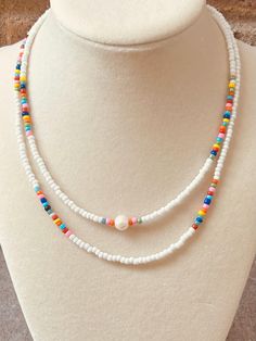 White seed bead necklace with rainbow accent beads and freshwater pearl focal bead. Crystal Lake, Seed Bead Necklace, Focal Bead, Rainbow Colors, Freshwater Pearls, Seed Beads, Jewelry Necklace Pendant, Beaded Necklace, Jewelry Necklaces