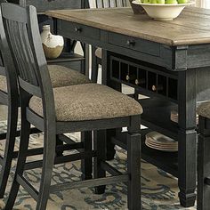 a dining room table with chairs and a bowl of fruit on it