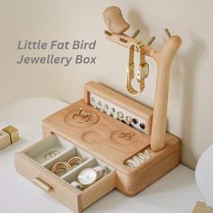 a wooden jewelry box with rings, bracelets and ring boxes in it on a table