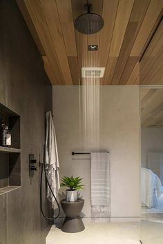 a modern bathroom with wood ceiling and white tile flooring, shower head, and towel rack