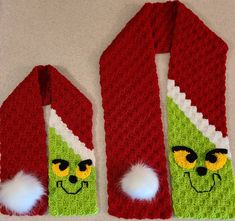 two knitted scarfs with green and red designs, one has a grin face on it