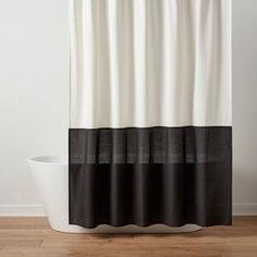 a shower curtain with black and white stripes on the bottom, in front of a bathtub