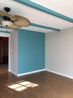 an empty room with blue walls and ceiling fans