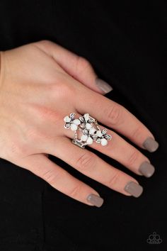 a woman's hand wearing a ring with white flowers on the middle of it