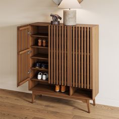 a wooden cabinet with two doors open and shoes on the bottom shelf next to it