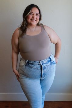 a woman standing in front of a wall with her hands on her hips and smiling