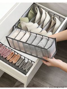 an open drawer with several pairs of shoes in it and someone's hand reaching for them