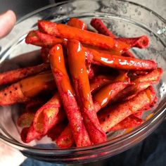 a glass bowl filled with hot dogs covered in ketchup