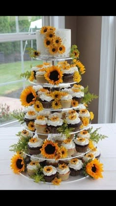 a tiered cake with cupcakes and sunflowers on it