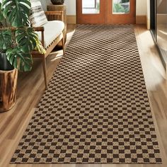 a brown and black checkered area rug in front of a door with potted plants