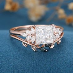 a princess cut diamond ring with leaves on the band and side stones in rose gold