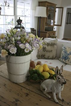 a rabbit sitting on top of a wooden table next to a vase filled with flowers