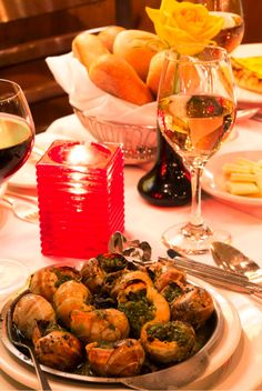 there is a plate of food on the table with wine and bread in the background