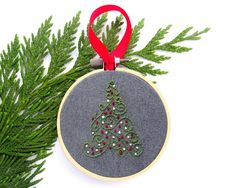 a christmas ornament hanging from a tree branch with a red ribbon around it