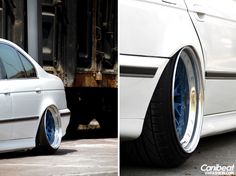 a white car with blue rims parked in front of a truck