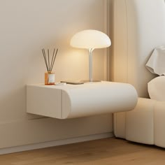 a white table with a lamp on it next to a bed