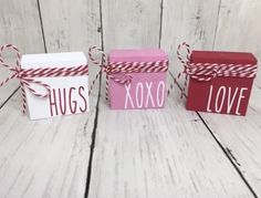 three small boxes with red and white string tied around the edges, one has hugs written on it