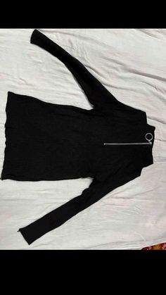 a woman's black top is laying on a white sheet and has a zipper in it