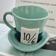 a tea cup and saucer sitting on top of a table next to a book