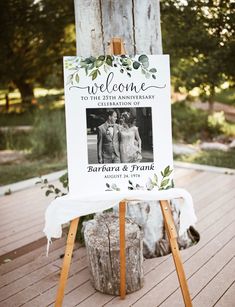 a welcome sign is on an easel with greenery around it and the couple's wedding date