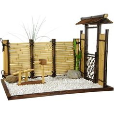 a small bamboo fence with rocks and gravel around it, along with a wooden bench