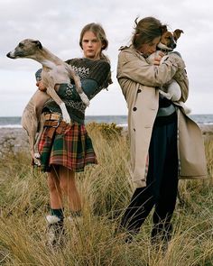 two women standing next to each other with dogs on their shoulders and one woman holding a dog in her arms