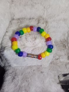 A rainbow themed bracelet with a wooden bead Rainbow Beaded Bracelets With Spacer Beads For Friendship, Casual Rainbow Bracelets With 8mm Beads, Rainbow Colored Round Beaded Bracelet For Friendship, Multicolor 8mm Beaded Wristband, Multicolor Wristband With Colorful Round Beads, Multicolor Wristband With Large Round Beads, Multicolor Round Beaded Wristband, Rainbow Bracelets With Letter Beads, Rainbow Bracelets With Large Beads As Gift