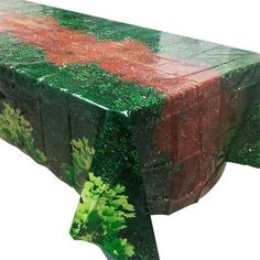 a table covered in green, red and brown paint with trees on it's sides