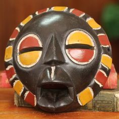 an african mask is sitting on top of a wooden table