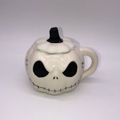 a ceramic teapot with a face painted on it's side and black eyes