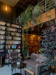 a living room filled with furniture and lots of greenery on the wall next to bookshelves