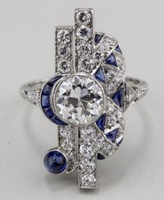 "𝐃𝐞𝐬𝐜𝐫𝐢𝐩𝐭𝐢𝐨𝐧 : *Antique Old European Cut Diamond Woman's Ring, Vintage Sapphire Diamond Ring, Edwardian Art Deco Ring, 925 Silver Wedding Ring, Fine Jewelry. ❖ 𝐃𝐢𝐚𝐦𝐨𝐧𝐝 𝐃𝐞𝐭𝐚𝐢𝐥𝐬 *Color : White, Blue *Clarity : VVS *Cut : Excellent *Center Stone Shape : Old European Cut *Center Stone Size : 7.00 MM *Center Stone Weight : 1.33 CT *Type : Cubic Zirconia (CZ) *We have all types of fancy & color Gemstone. For more queries please contact us immediately. ❖ 𝐑𝐢𝐧𝐠 𝐃𝐞𝐭𝐚𝐢𝐥𝐬 Luxury Sapphire Art Deco Jewelry, Collectible Platinum Ring In Silver Color, Collectible Silver Platinum Rings, White Multi-stone Platinum Jewelry, Vintage Multi-stone Diamond White Rings, White Art Deco Cluster Ring, Art Deco Multi-stone Platinum Diamond Ring, Art Deco Multi-stone Anniversary Rings, Vintage Diamond White Sapphire Jewelry