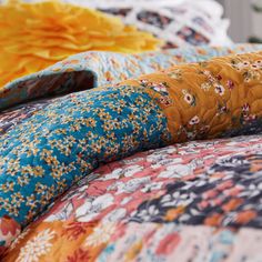 the bed is covered with many different colored sheets and pillows, including one that has flowers on it