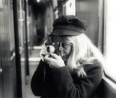 black and white photograph of a woman taking a photo on a train with her camera