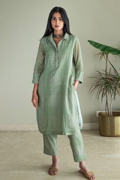 Green shirt kurta with zari jamdani checkered in silver zari woven motifs. Paired with pant.
Components: 2
Pattern: Woven
Type Of Work: Zari, checkered
Neckline: Collar
Sleeve Type: Three quarter
Fabric: Kurta: Zari Jamdani Checks Muslin, Lining: Shantoon
Color: Green
Other Details: 
Side pockets
Embroidered placket
Front concealed button placket
Rounded hem
Attached lining
Note: Necklace worn by the model is not for sale
Disclaimer: The fabric, color and texture of the final garment might have Shorshe Clothing, Collar Kurti Design, Collar Kurti, Stylish Kurtis Design, Kurta Patterns, Green Checkered, Simple Kurta Designs, Kurta Style, Kurti Patterns