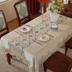 a dining room table set for four with plates and cups on the placemats