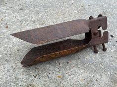 an old rusted metal object sitting on top of a cement ground next to a pair of scissors