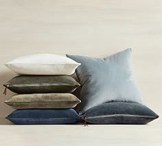 pillows stacked on top of each other in front of a white wall with a light colored background