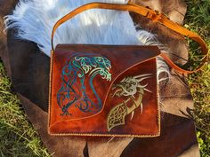 This hand-tooled leather bag is made from 5-7 oz leather and hand-stitched. It's covered with a resolene finish for a long-lasting item. The bag is 8.5 in tall, 11 in wide, and 4 in deep. Strap has a buckle for adjustments. Hand Tooled Leather Shoulder Bag As Gift, Hand Tooled Leather Shoulder Bag For Gift, Leather Hand Tooled Shoulder Bag Gift, Leather Hand Tooled Saddle Bag For Daily Use, Leather Satchel Bag With Embossed Details, Leather Embossed Satchel For Everyday Use, Everyday Embossed Leather Satchel, Hand-stitched Leather Shoulder Bag Gift, Embossed Leather Shoulder Bag