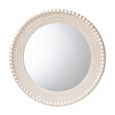 a white round mirror with beading around it