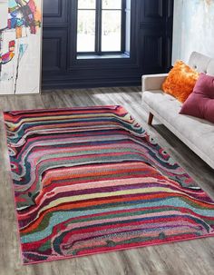 a living room with a couch, rug and window in the background that is decorated with multicolored stripes