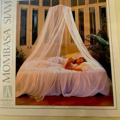 a woman laying on top of a bed covered in a white mosquito net