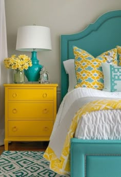 a bedroom with yellow and blue decor on the bed, nightstands and dresser in front of it